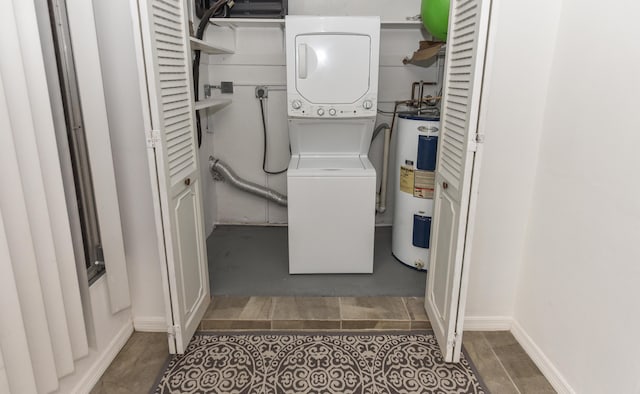 laundry room featuring estacked washer and dryer, water heater, and baseboards