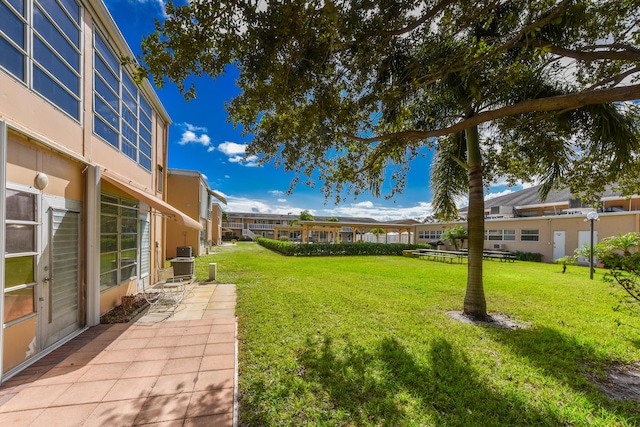 view of green lawn with central AC unit and a patio