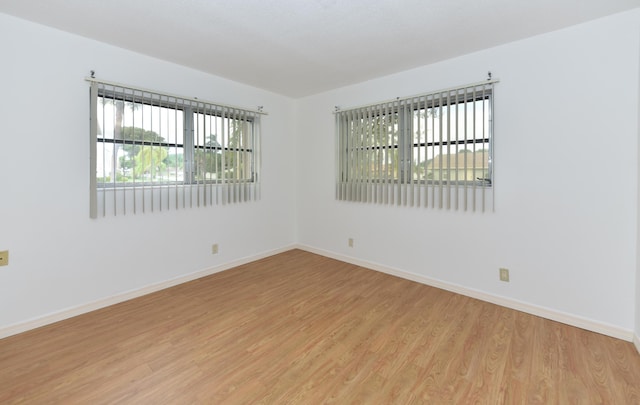 unfurnished room featuring healthy amount of natural light, light wood-type flooring, and baseboards