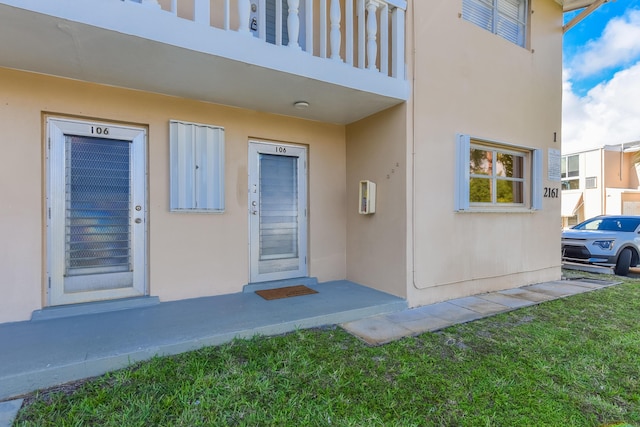 entrance to property featuring stucco siding and a yard
