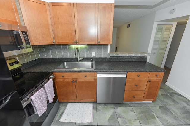 kitchen featuring stainless steel appliances, a sink, backsplash, and dark countertops