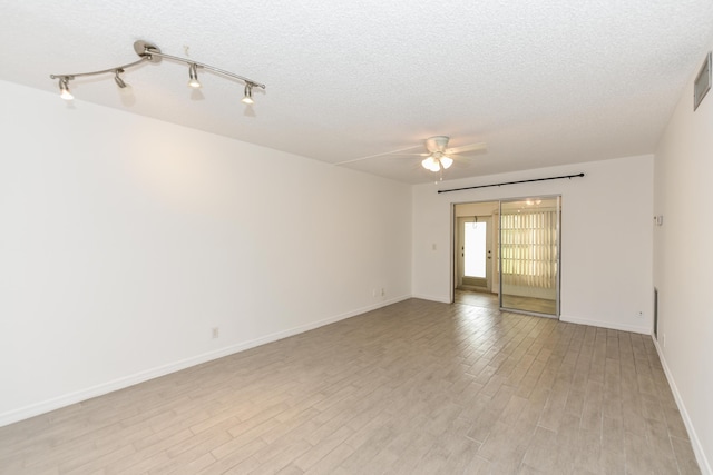 unfurnished room with a ceiling fan, a textured ceiling, light wood-style flooring, and baseboards