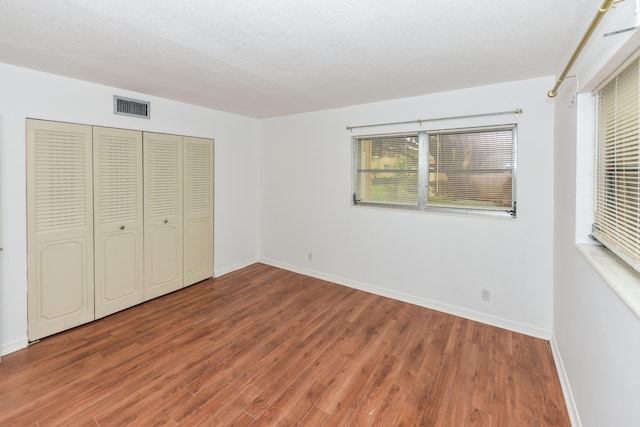 unfurnished bedroom featuring hardwood / wood-style flooring, a textured ceiling, and a closet