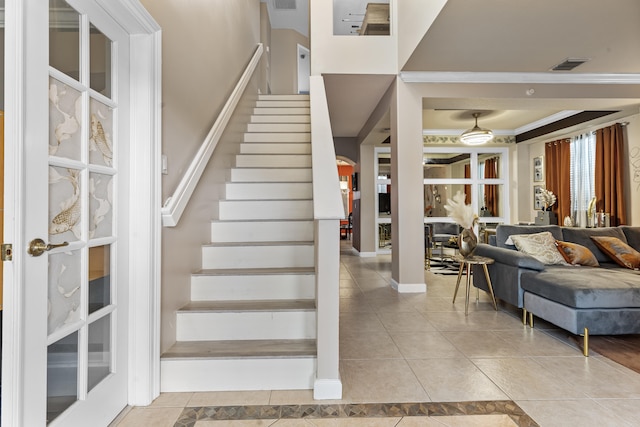 stairs with ornamental molding and tile patterned floors