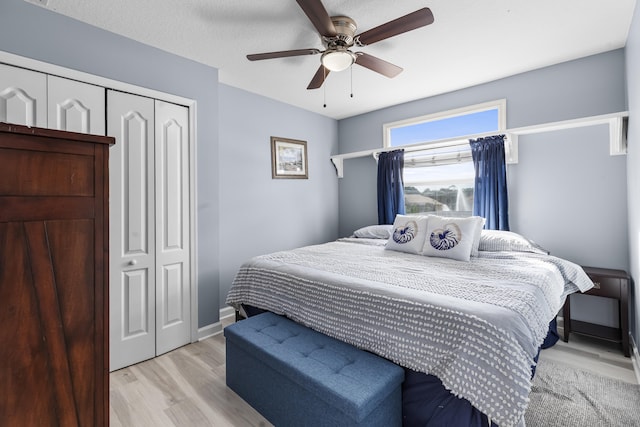 bedroom with light hardwood / wood-style flooring, ceiling fan, and a closet