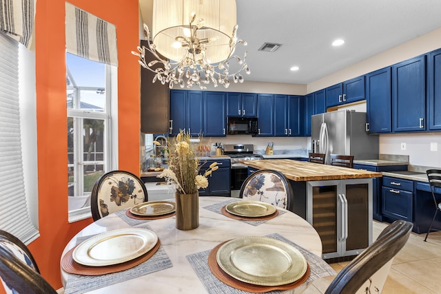 kitchen featuring blue cabinetry, appliances with stainless steel finishes, light tile patterned flooring, and a chandelier