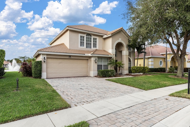 mediterranean / spanish house featuring a garage and a front lawn