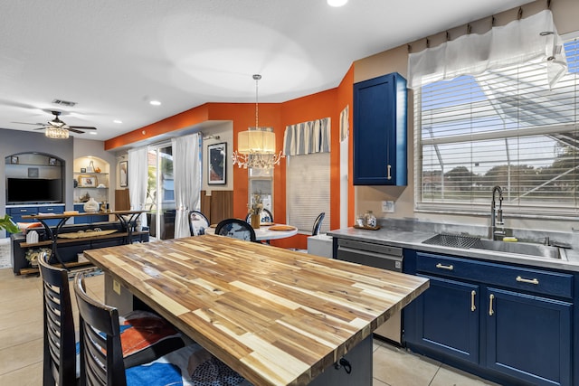 kitchen featuring sink, light tile patterned floors, blue cabinetry, butcher block countertops, and decorative light fixtures