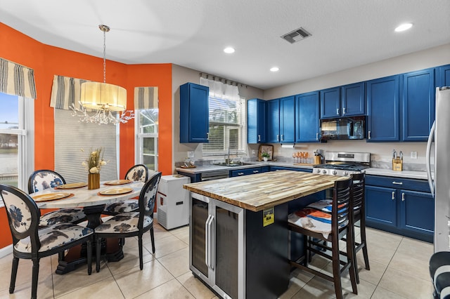 kitchen featuring an inviting chandelier, appliances with stainless steel finishes, hanging light fixtures, and blue cabinets