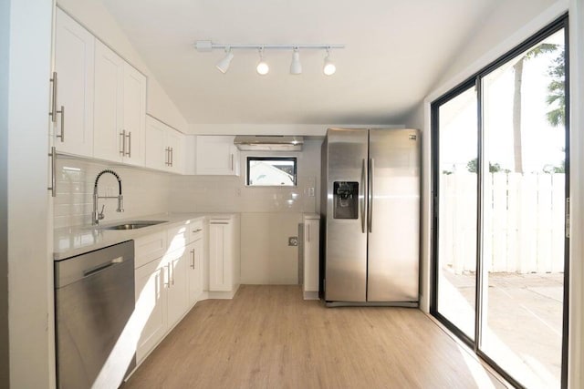 kitchen with light wood-type flooring, stainless steel appliances, backsplash, sink, and white cabinetry