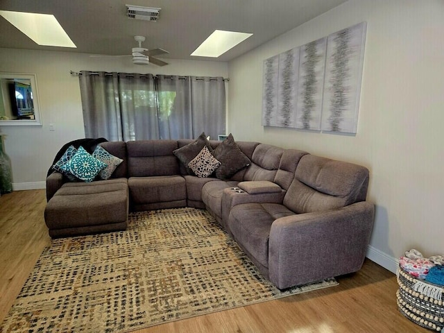 living room featuring a skylight, hardwood / wood-style floors, and ceiling fan