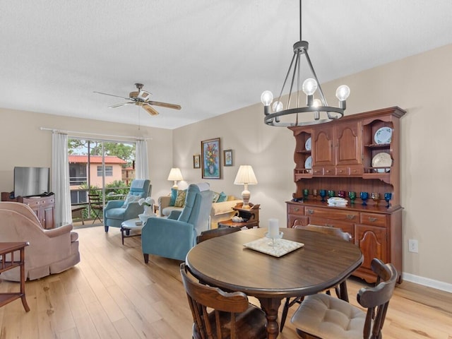 dining room featuring ceiling fan with notable chandelier and light hardwood / wood-style flooring