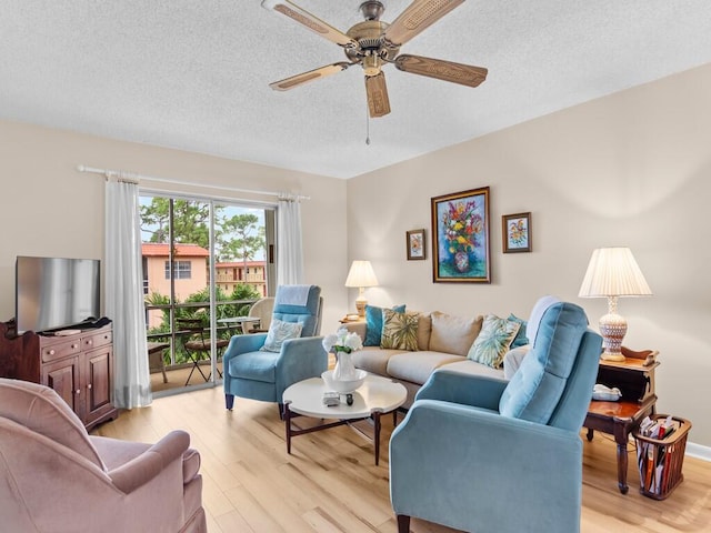 living room featuring light wood-type flooring, a textured ceiling, and ceiling fan