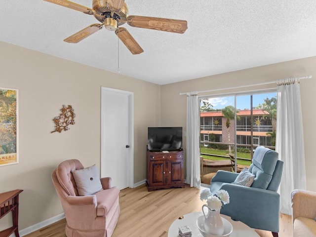 living room with light wood-type flooring, a textured ceiling, and ceiling fan