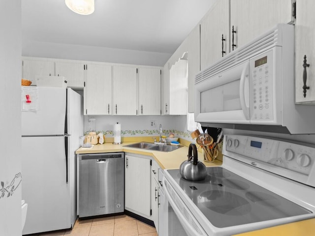 kitchen featuring white appliances, white cabinetry, sink, and light tile patterned flooring