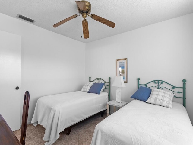 carpeted bedroom featuring ceiling fan and a textured ceiling