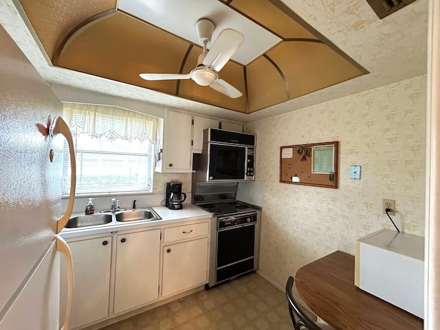 kitchen featuring ceiling fan, range, white refrigerator, and sink