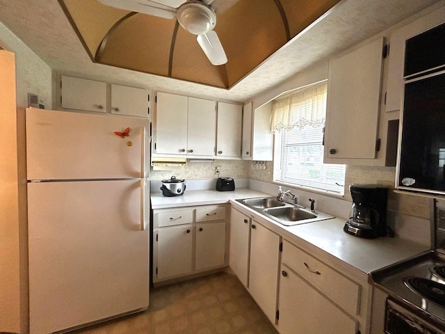 kitchen with backsplash, white refrigerator, sink, and ceiling fan