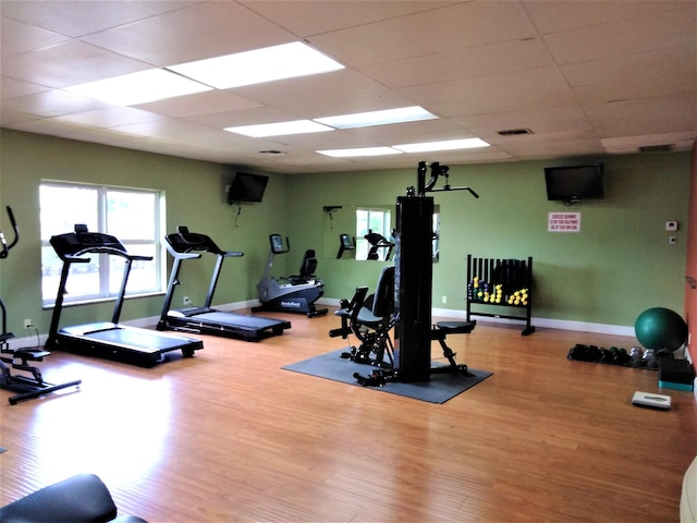 workout area featuring wood finished floors, a drop ceiling, and baseboards