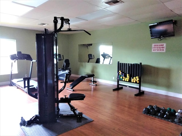 workout area featuring baseboards, a drop ceiling, and wood finished floors