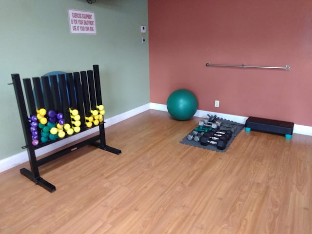 exercise area with baseboards and wood finished floors