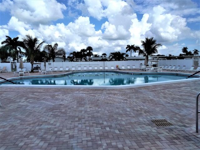 community pool featuring fence and a patio