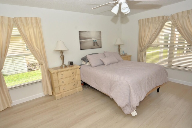 bedroom featuring a textured ceiling, light hardwood / wood-style flooring, multiple windows, and ceiling fan