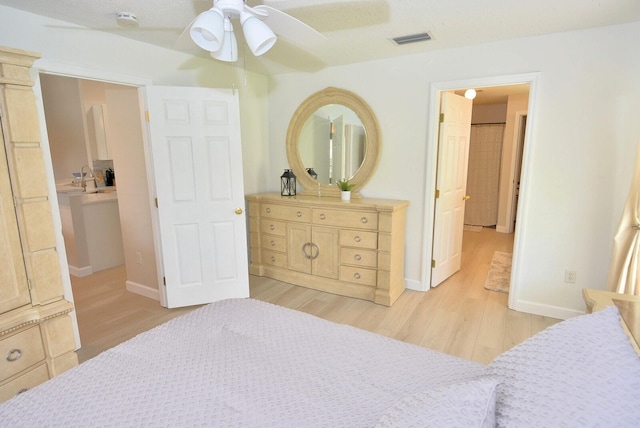 bedroom with ensuite bath, a textured ceiling, ceiling fan, and light hardwood / wood-style flooring