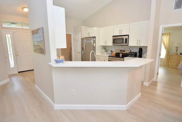 kitchen featuring stainless steel appliances, kitchen peninsula, high vaulted ceiling, light hardwood / wood-style flooring, and white cabinets