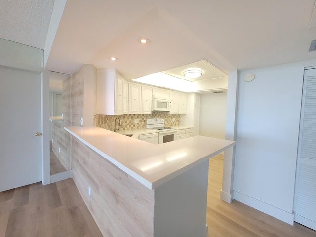 kitchen featuring kitchen peninsula, white appliances, light hardwood / wood-style floors, and white cabinets