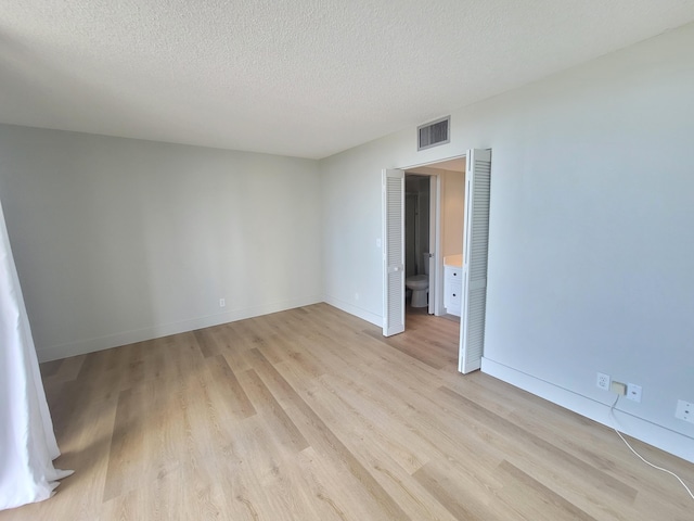 spare room with light hardwood / wood-style flooring and a textured ceiling