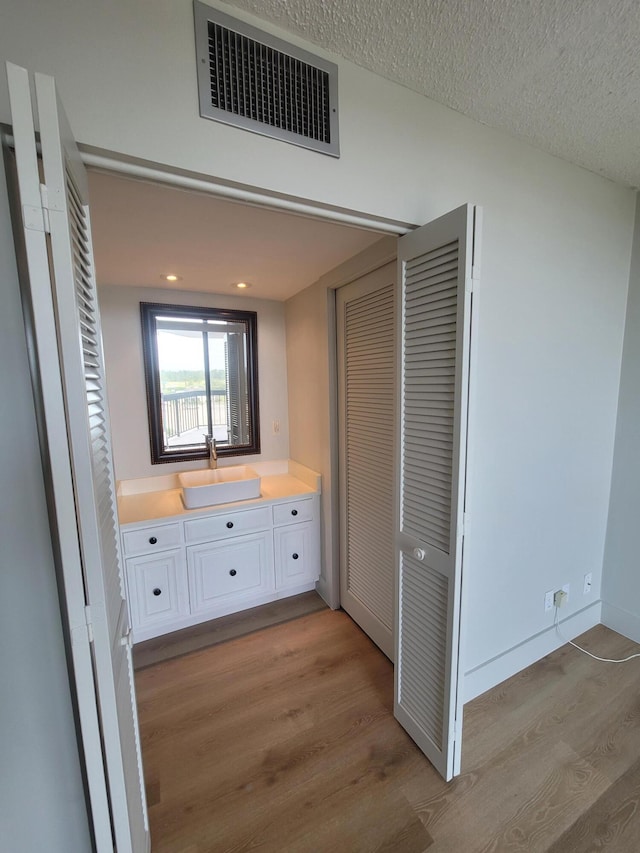 bathroom featuring hardwood / wood-style floors, vanity, and a textured ceiling