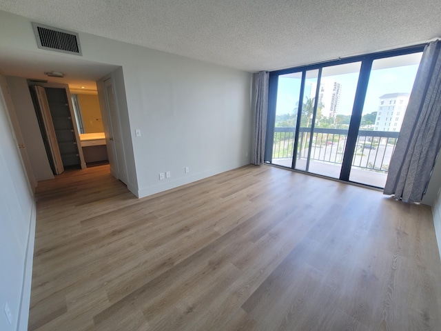 empty room featuring wood-type flooring, a textured ceiling, and floor to ceiling windows