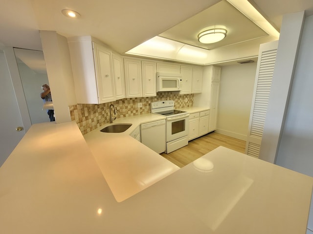 kitchen with light hardwood / wood-style floors, sink, white appliances, white cabinets, and decorative backsplash