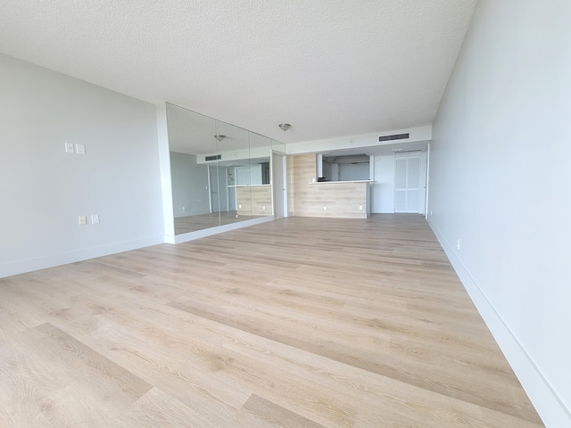 unfurnished living room featuring a textured ceiling and light hardwood / wood-style flooring