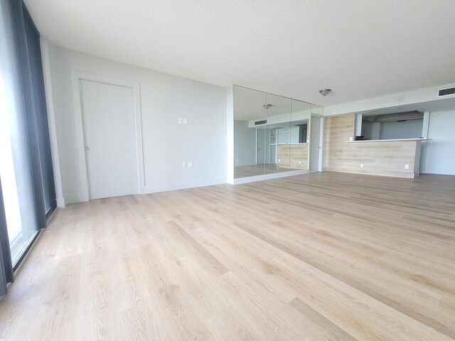 unfurnished living room with a textured ceiling and light hardwood / wood-style flooring