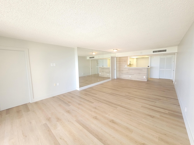 unfurnished room with a textured ceiling and light hardwood / wood-style flooring