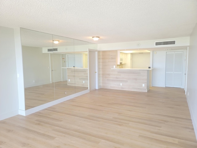 empty room featuring a textured ceiling and light hardwood / wood-style flooring