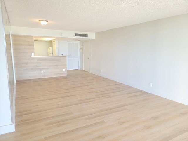 unfurnished room with a textured ceiling and light hardwood / wood-style floors