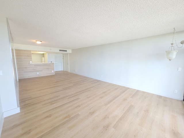 unfurnished living room with light hardwood / wood-style flooring and a textured ceiling