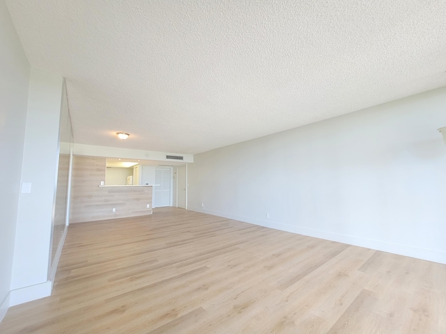 unfurnished living room with light hardwood / wood-style floors and a textured ceiling