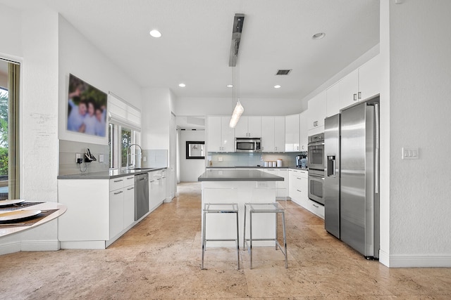 kitchen featuring appliances with stainless steel finishes, a kitchen breakfast bar, sink, white cabinets, and a center island