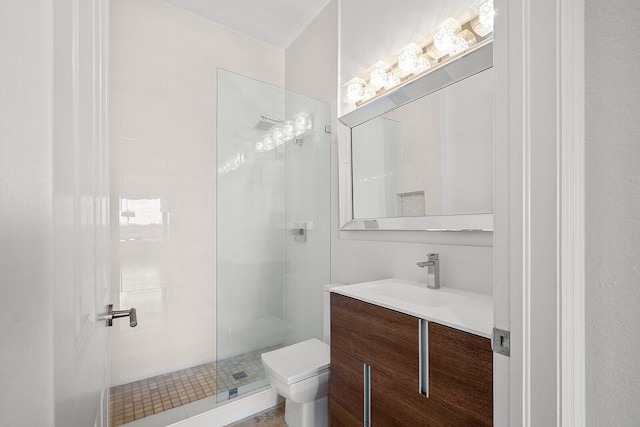 bathroom with toilet, vanity, and tiled shower