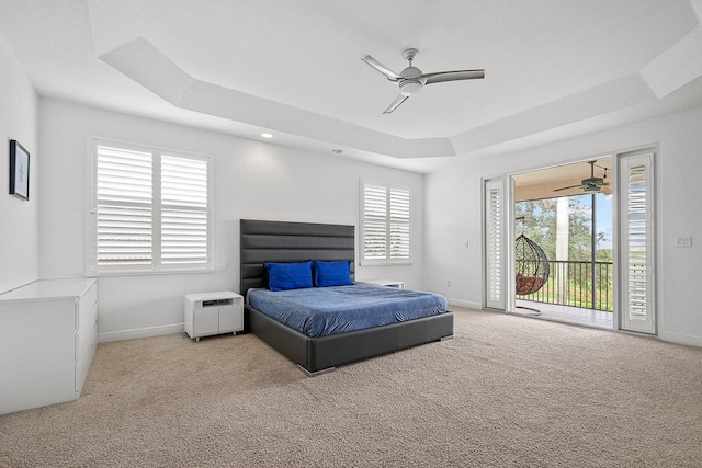 bedroom with a tray ceiling, ceiling fan, light colored carpet, and access to outside