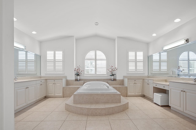 bathroom with vanity, vaulted ceiling, tile patterned floors, and tiled tub