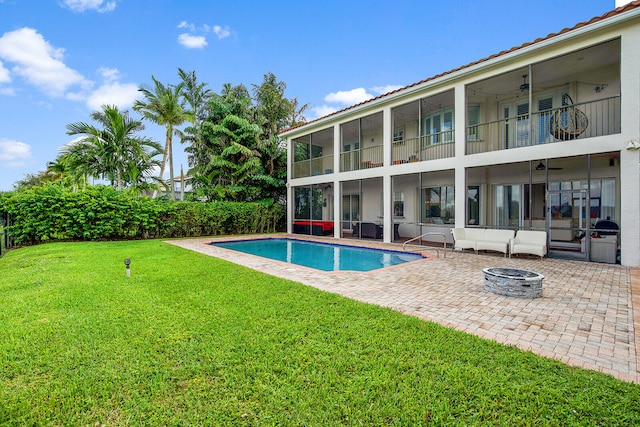 view of swimming pool featuring a lawn, ceiling fan, a patio area, and an outdoor fire pit