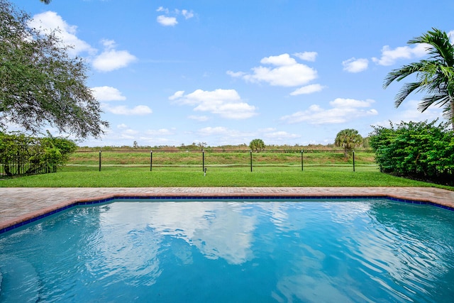 view of swimming pool featuring a lawn and a rural view