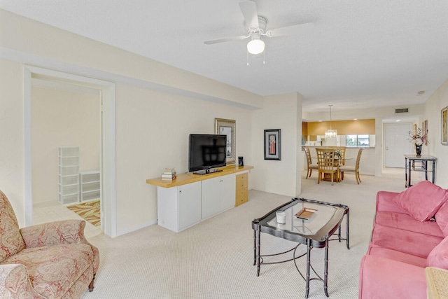 living room with ceiling fan with notable chandelier and light colored carpet