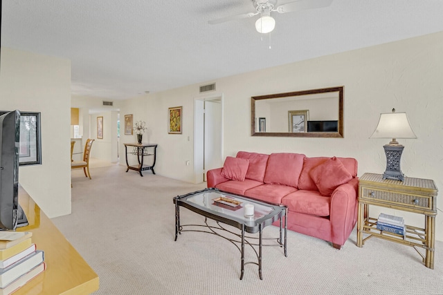 carpeted living room featuring ceiling fan and a textured ceiling