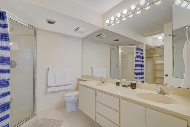 bathroom with toilet, vanity, tile patterned floors, and a shower with door